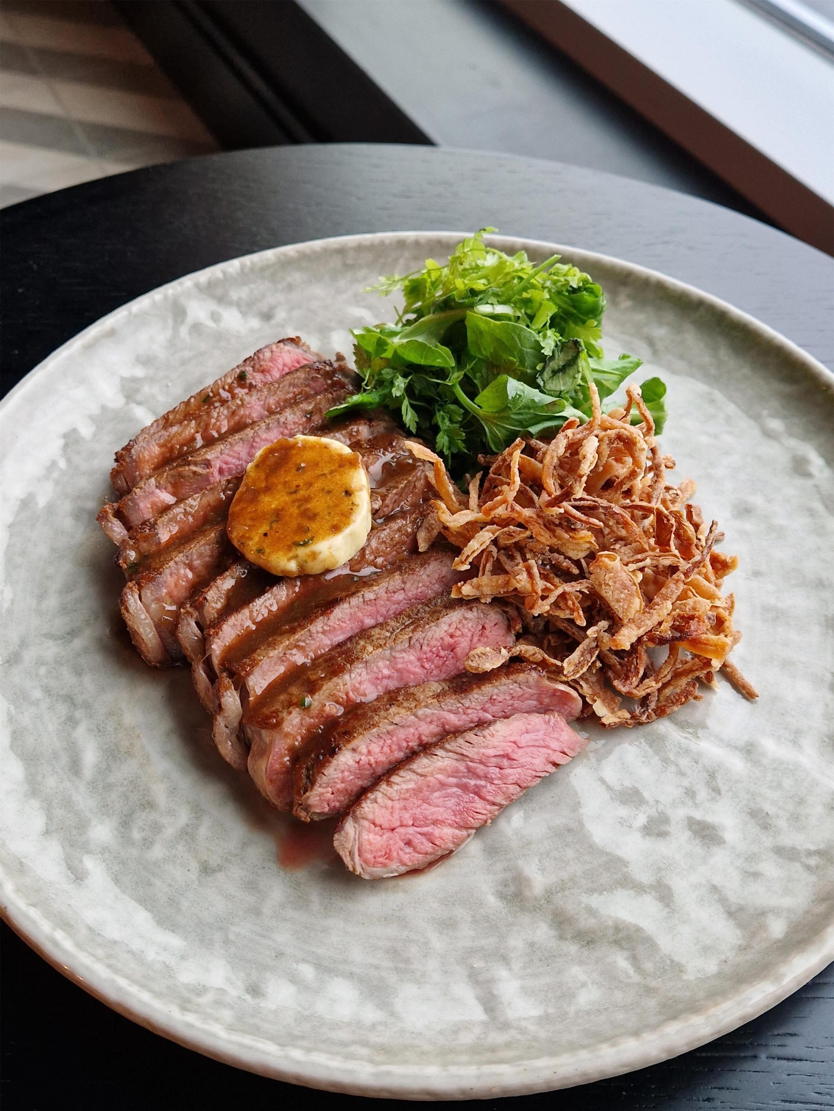 Ein Teller mit geschnittenem Fleisch, gebratenen Zwiebeln und einem Salatbeilag.