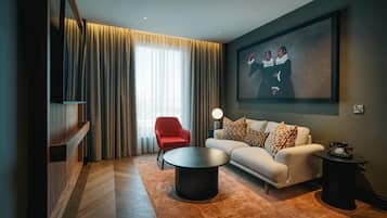 Una sala de estar moderna con un sofá, un sillón rojo y una mesa de centro redonda.