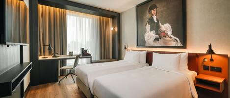 A hotel room with two beds, a desk, a chair, a desk lamp, a coffee maker, and a painting on the wall.