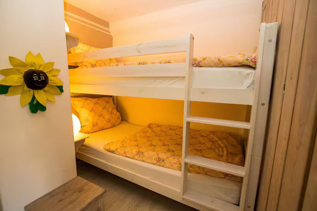 Una cama litera con un colchón estampado con motivos florales y una escalera de madera.