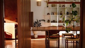 A dining area with a wooden table and chairs, surrounded by shelves with various decorative items and plants. - Maison St Rémy Centre Piscine Chauffée et Hammam (Saint-Rémy-de-Provence)