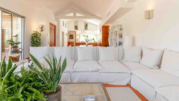 A modern living room with a white sectional sofa, a coffee table, and various potted plants. - Maison St Rémy Centre Piscine Chauffée et Hammam (Saint-Rémy-de-Provence)