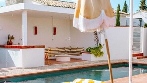 A poolside area with a lounge chair, a small table, and a potted plant. - Maison St Rémy Centre Piscine Chauffée et Hammam (Saint-Rémy-de-Provence)