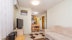 A living room with a TV, sofa, and dining area with chairs and a table. - Ferienwohnung Maya Lorena (Baska)