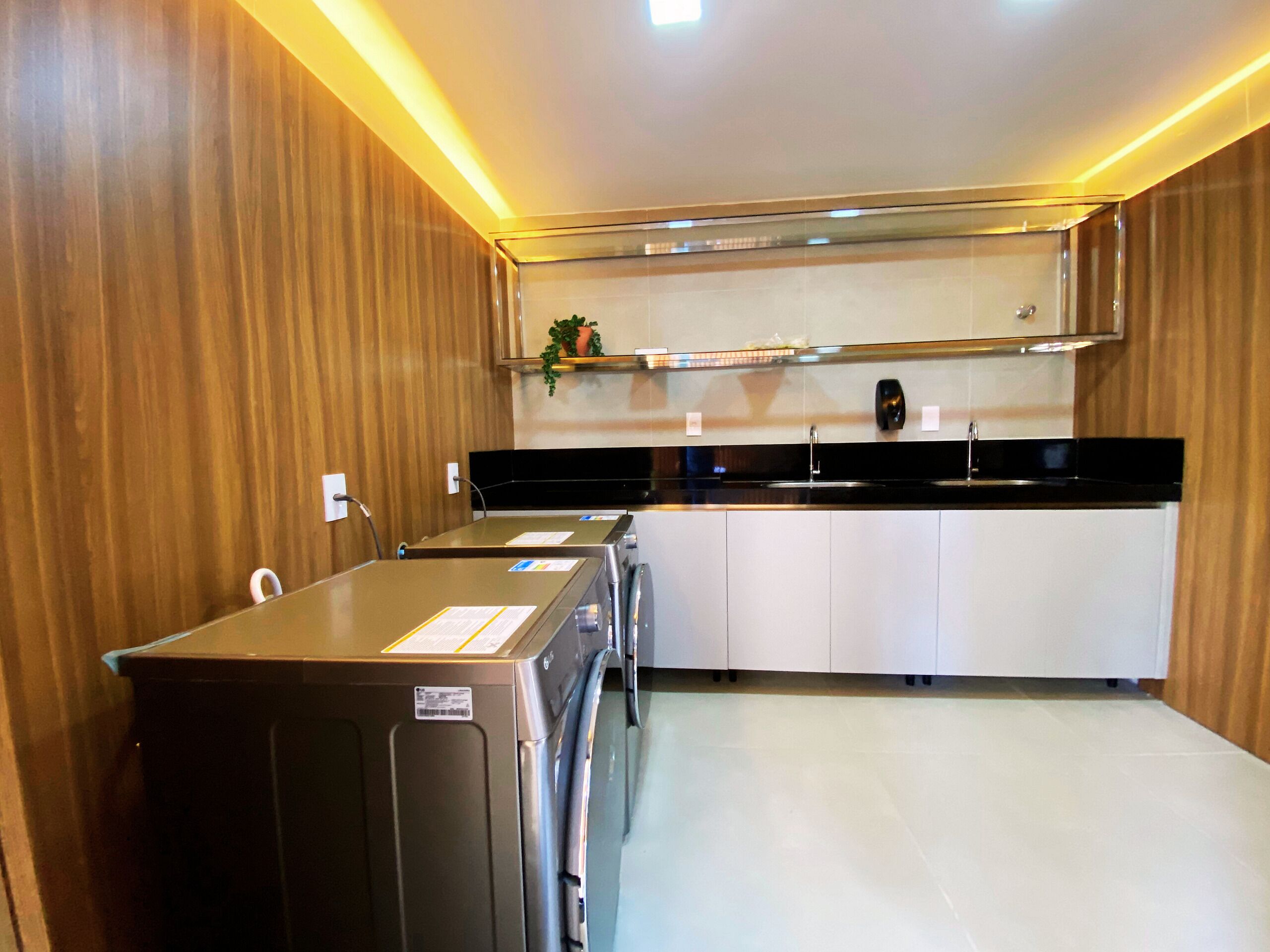 Una cocina moderna con un refrigerador de acero inoxidable, una encimera negra y armarios blancos.