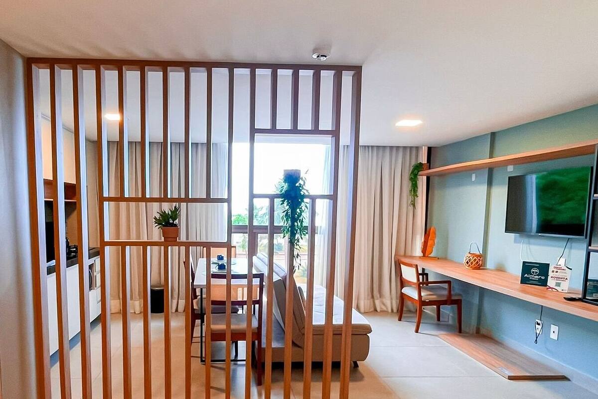 Un salon moderne comprenant un coin repas, un téléviseur fixé au mur et une cloison en bois.