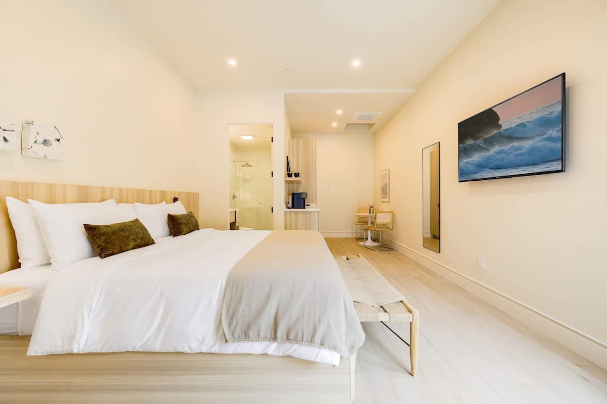 Relax in this serene bedroom with a large bed, bedside tables, and a framed seascape.