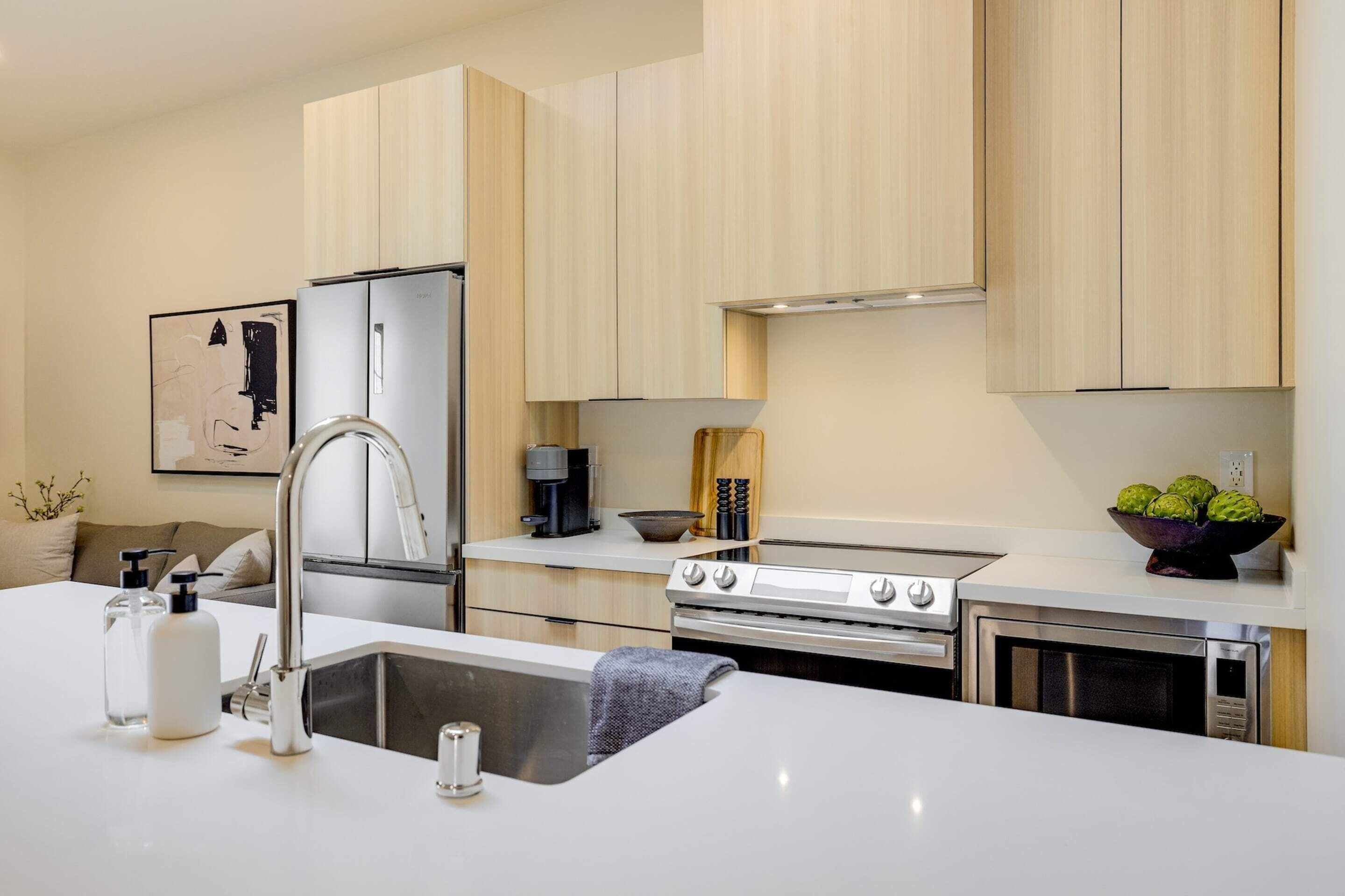A modern kitchen with a stainless steel refrigerator, double sink, and a large stove.