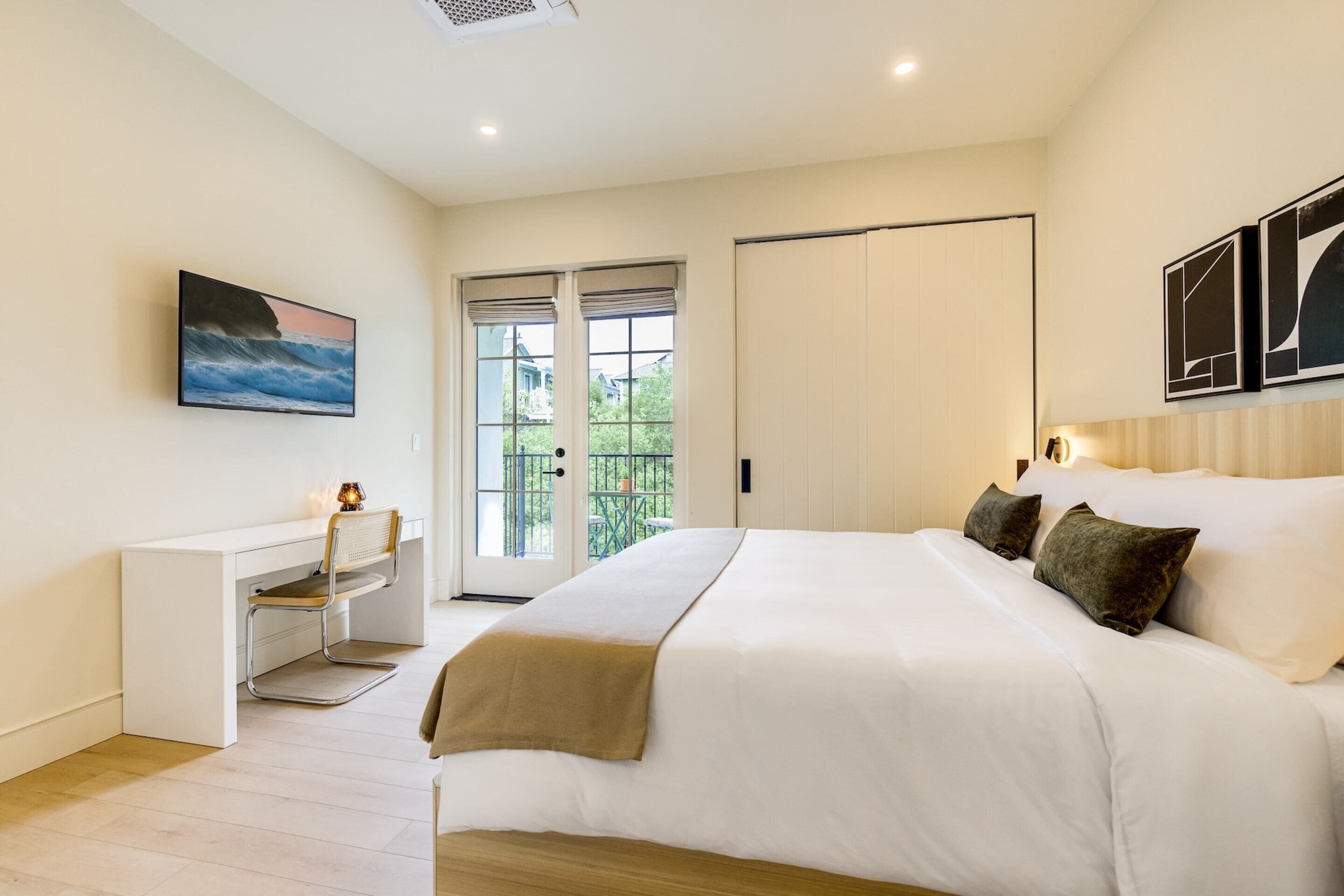 Une chambre moderne avec un grand lit, un bureau et une vue sur l’extérieur.