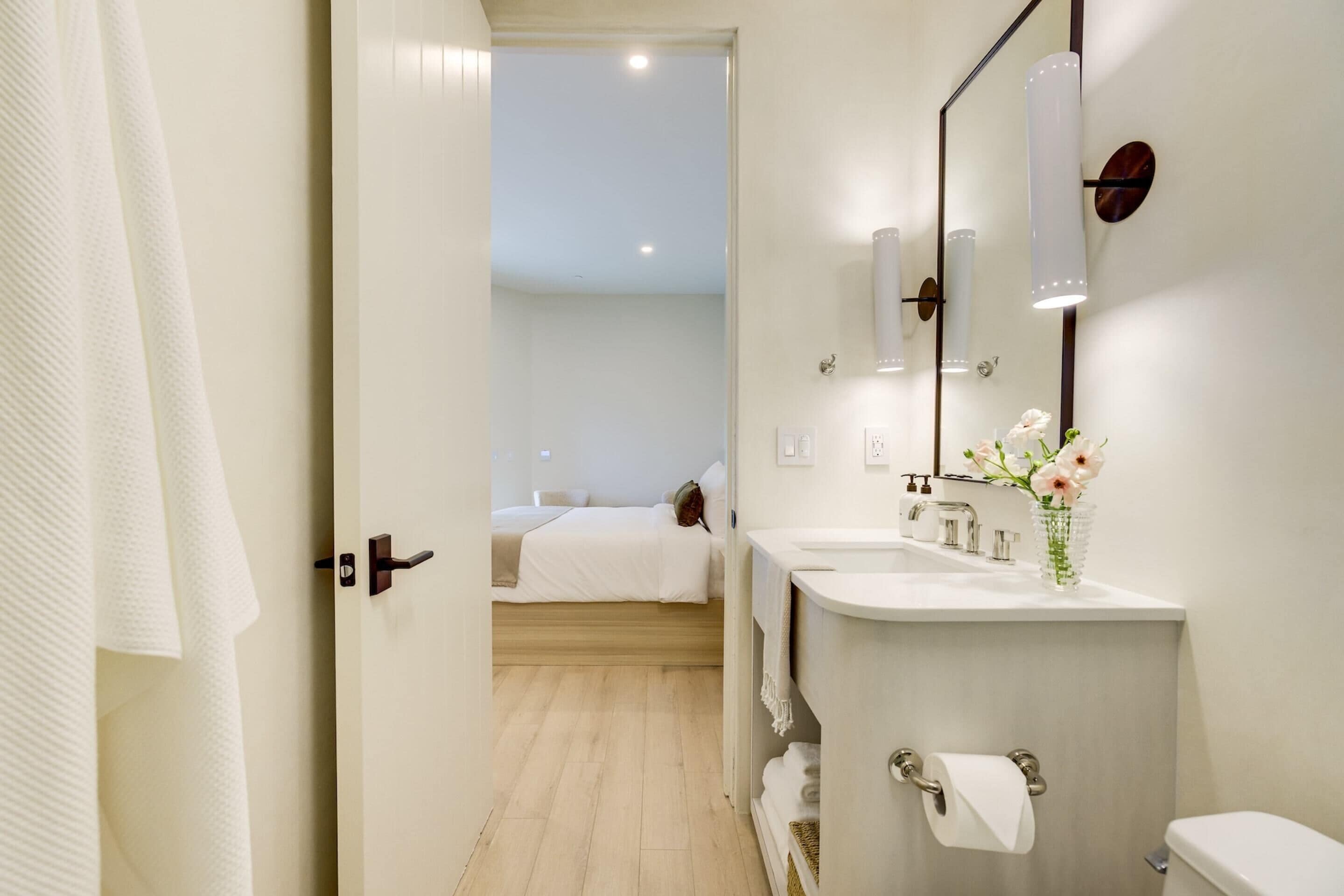 Ein modernes Badezimmer mit großem Spiegel, zwei Waschbecken und Toilette.