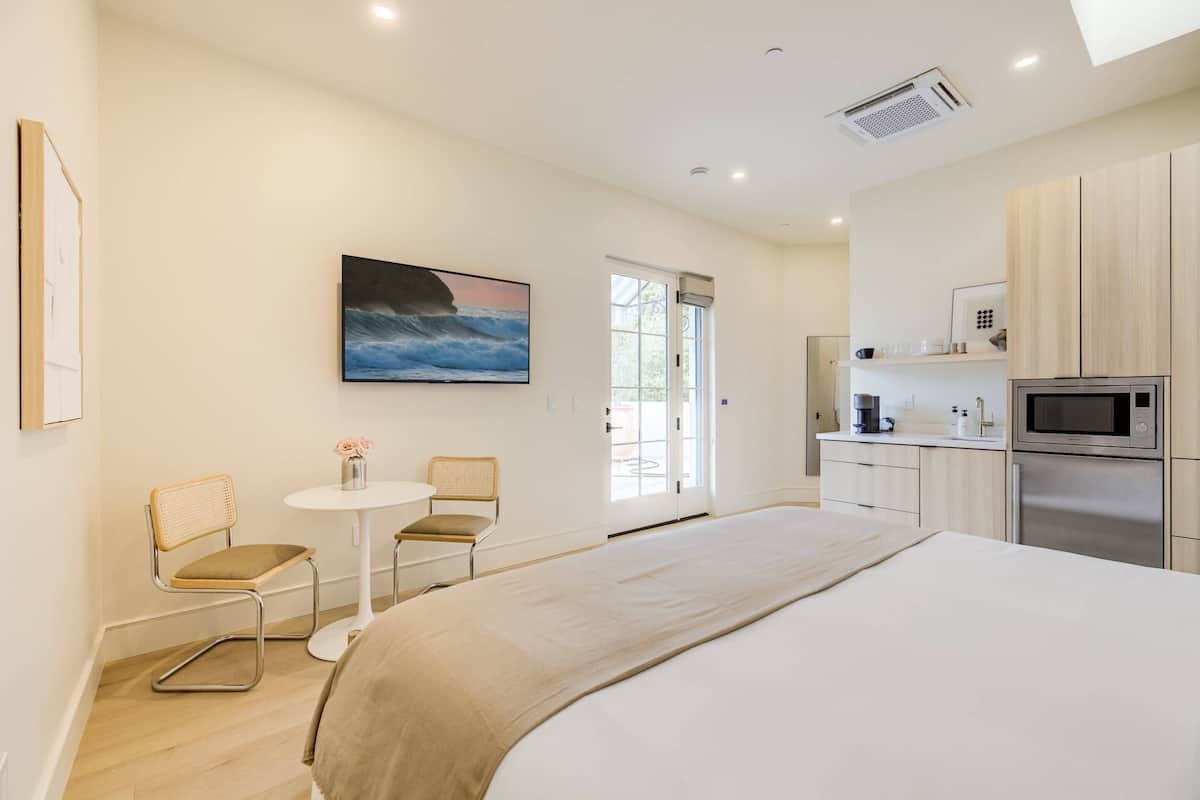 Relax in a serene space with a large bed, a small table, and a wall-mounted seascape painting.