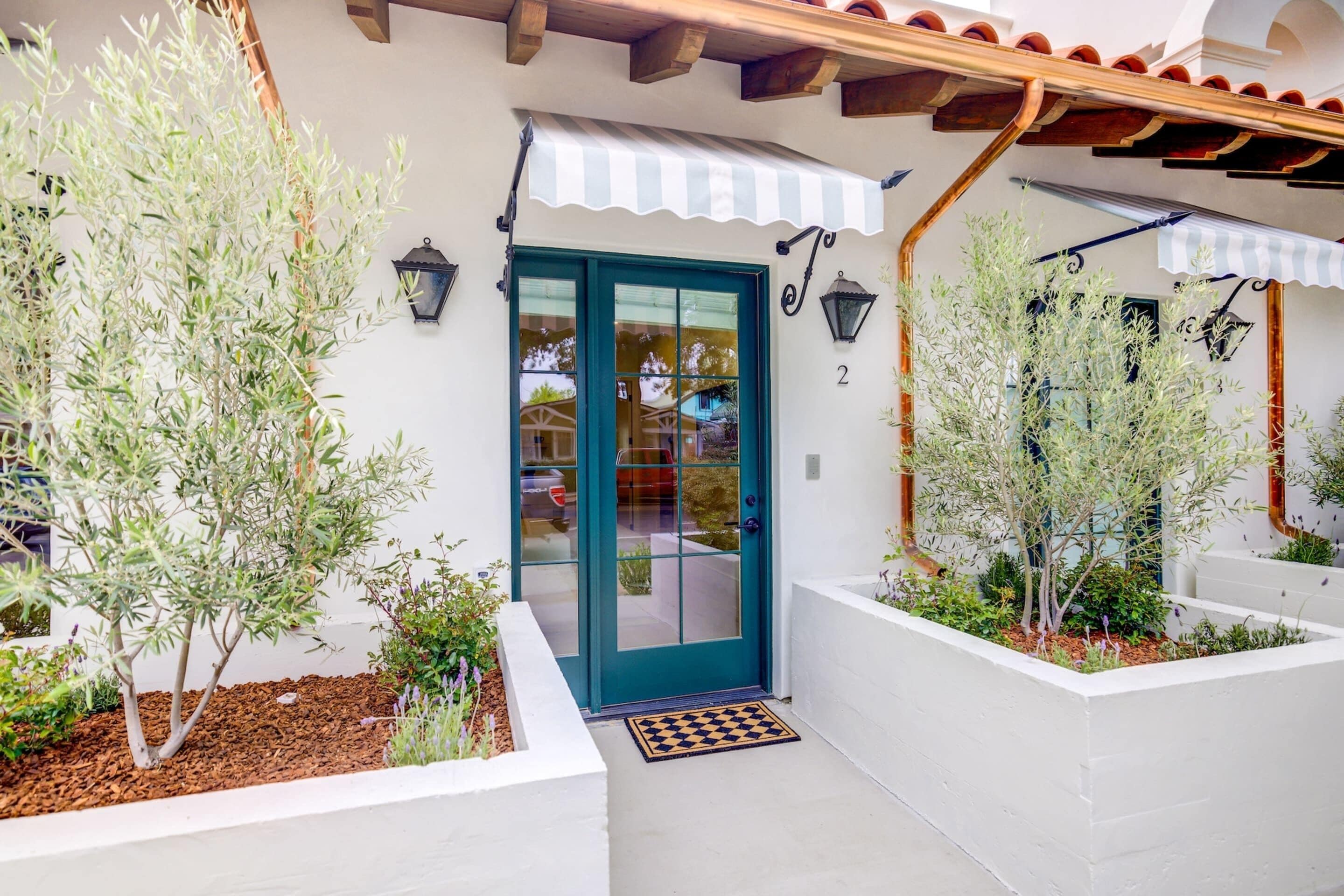 A building with a teal door, white walls, and a striped awning.