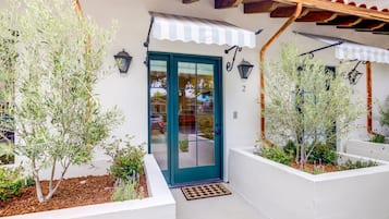 A building with a teal door, white walls, and a striped awning.