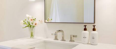 A bathroom with a white sink, a mirror, and two bottles of hand soap and lotion.