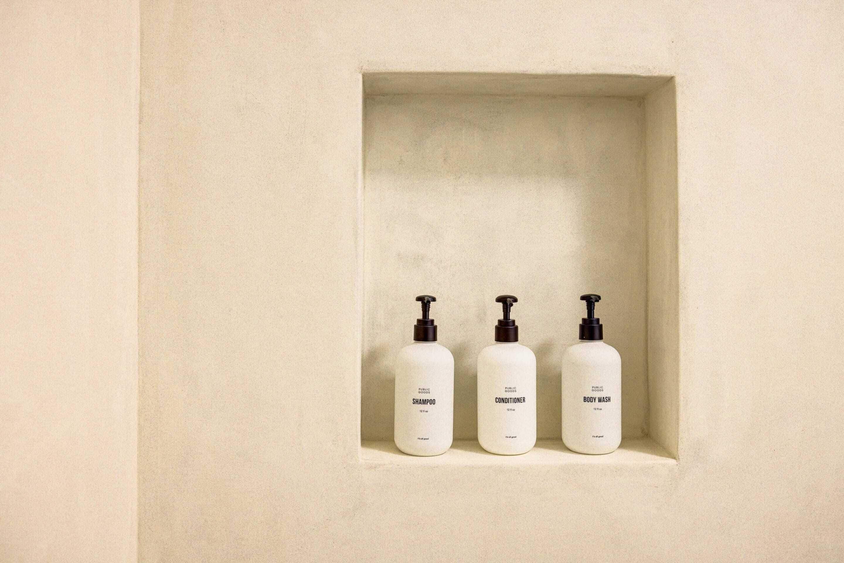 Three bottles of personal care products in a recessed shelf.