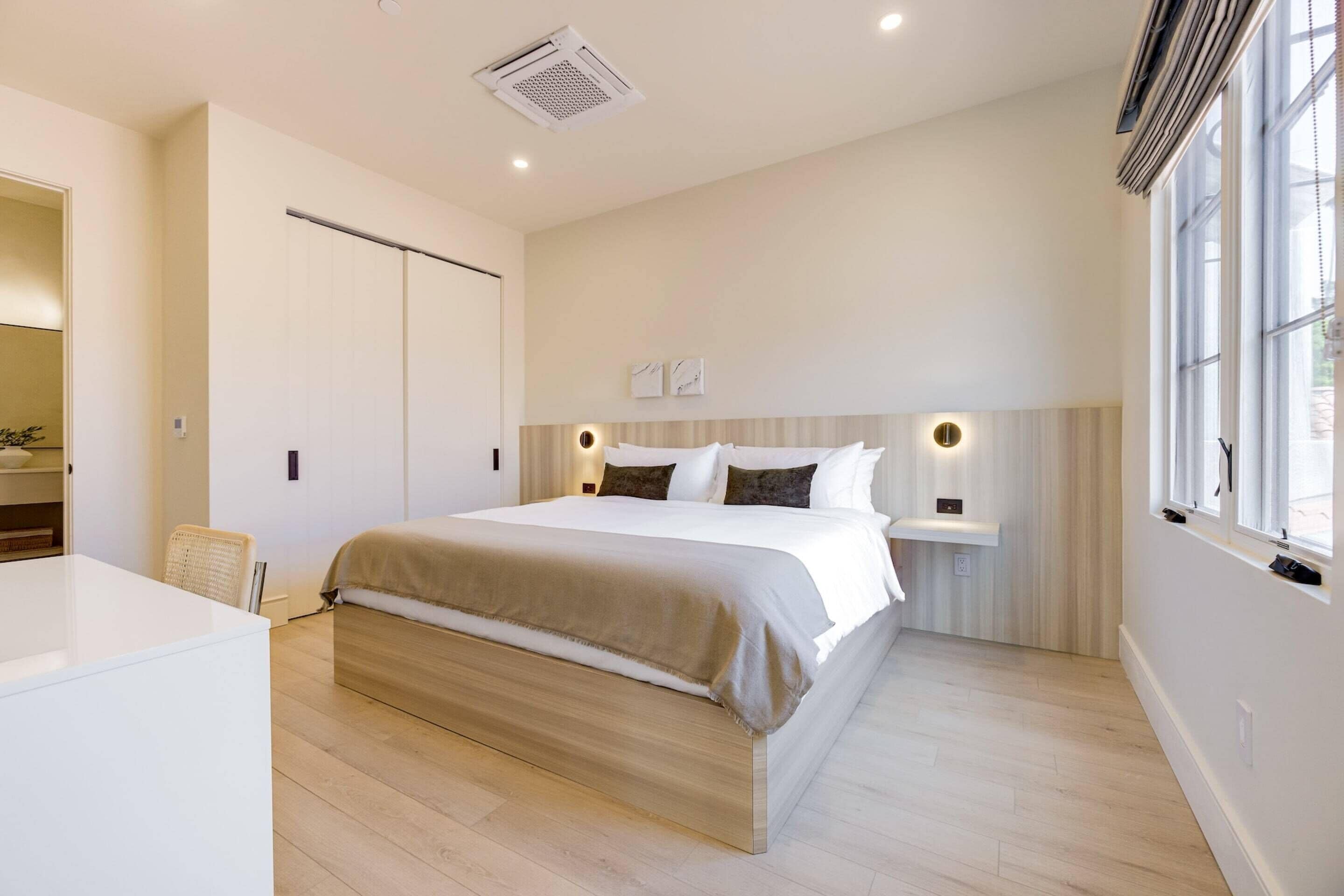 Een moderne slaapkamer met een groot bed, nachtkastjes en een raam.