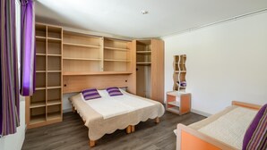 Un dormitorio con cama, armario de madera y rascador para gatos.