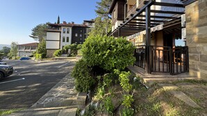 A residential building with a stone facade, a balcony with a metal railing, and a small garden area with shrubs. - Stunning 2-bed Apartment in Sozopol (Sozopol)