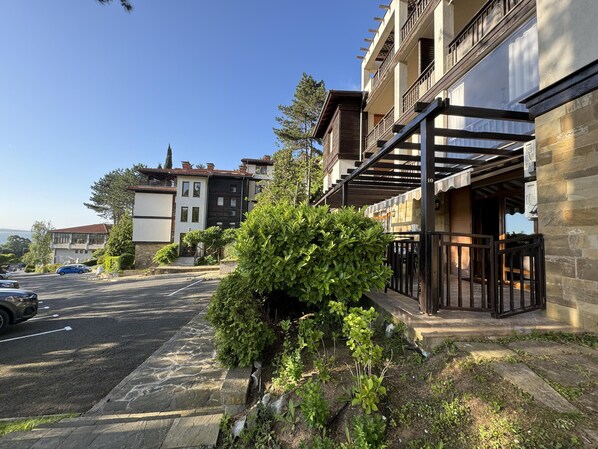 A residential building with a stone facade, a balcony with a metal railing, and a small garden area with shrubs. - Stunning 2-bed Apartment in Sozopol (Sozopol)