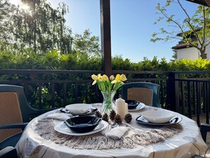 An outdoor dining area with round tables, chairs, and a vase with flowers. - Stunning 2-bed Apartment in Sozopol (Sozopol)