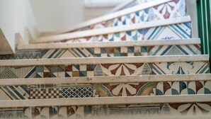 Una escalera con baldosas estampadas y barandilla verde.