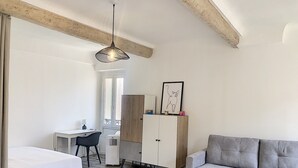 Un dormitorio moderno con una cama, un escritorio, una silla, un armario y un sofá gris.