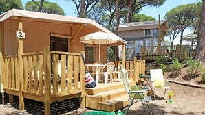 A wooden deck with a covered seating area, a number '2' sign, and a green inflatable alligator. - Barricata Holiday Village Lodge Tent Deluxe für 5 Personen (Porto)