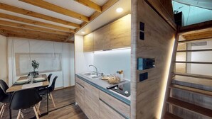 Una cocina moderna con vigas de madera, un lavamanos integrado y un comedor con mesa y sillas.