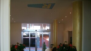A hotel lobby with a revolving door, potted plants, and a reception desk. - Robinia (Imperia)