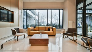 A modern living room with a large sofa, a coffee table, and a TV mounted on the wall. - Newly Furnished 1BR Suite w Balcony & Free Parking (Mississauga)