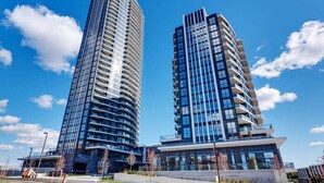 Two high-rise buildings with modern architecture, featuring curved balconies and large windows. - Newly Furnished 1BR Suite w Balcony & Free Parking (Mississauga)