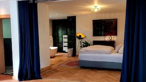 A modern bedroom with a large bed, a floor lamp, and a view of the outdoors. - Graceland In the Black Forest (Fischerbach)