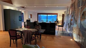 A modern kitchen with a dining area, a large window with a mountain view, and a decorative wall. - Graceland In the Black Forest (Fischerbach)