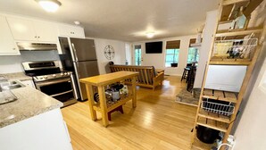 Une cuisine moderne dotée d’appareils électroménagers en acier inoxydable, d’une table en bois et d’un meuble à vin intégré.