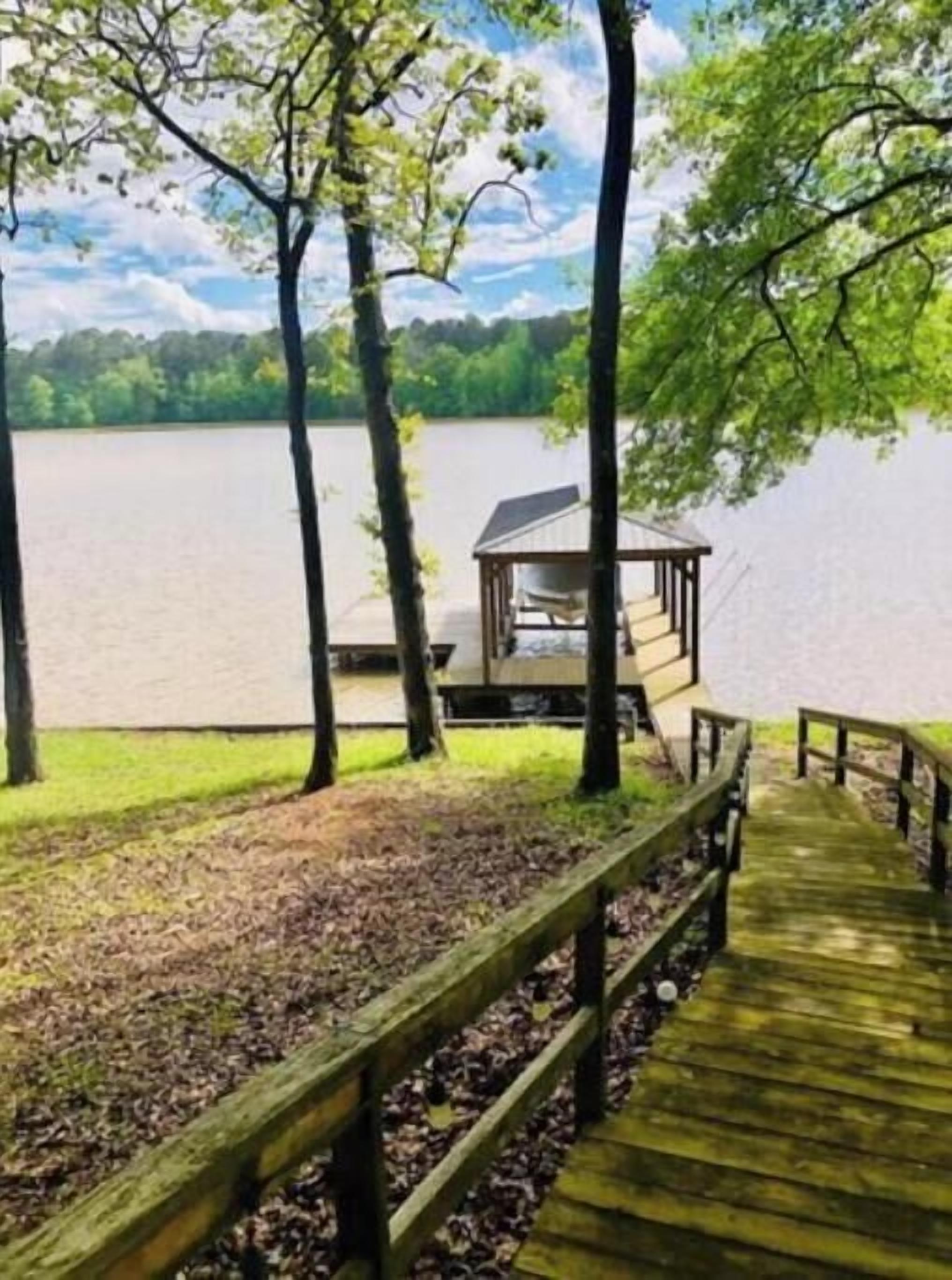 A wooden dock leading to a small gazebo by a lake.