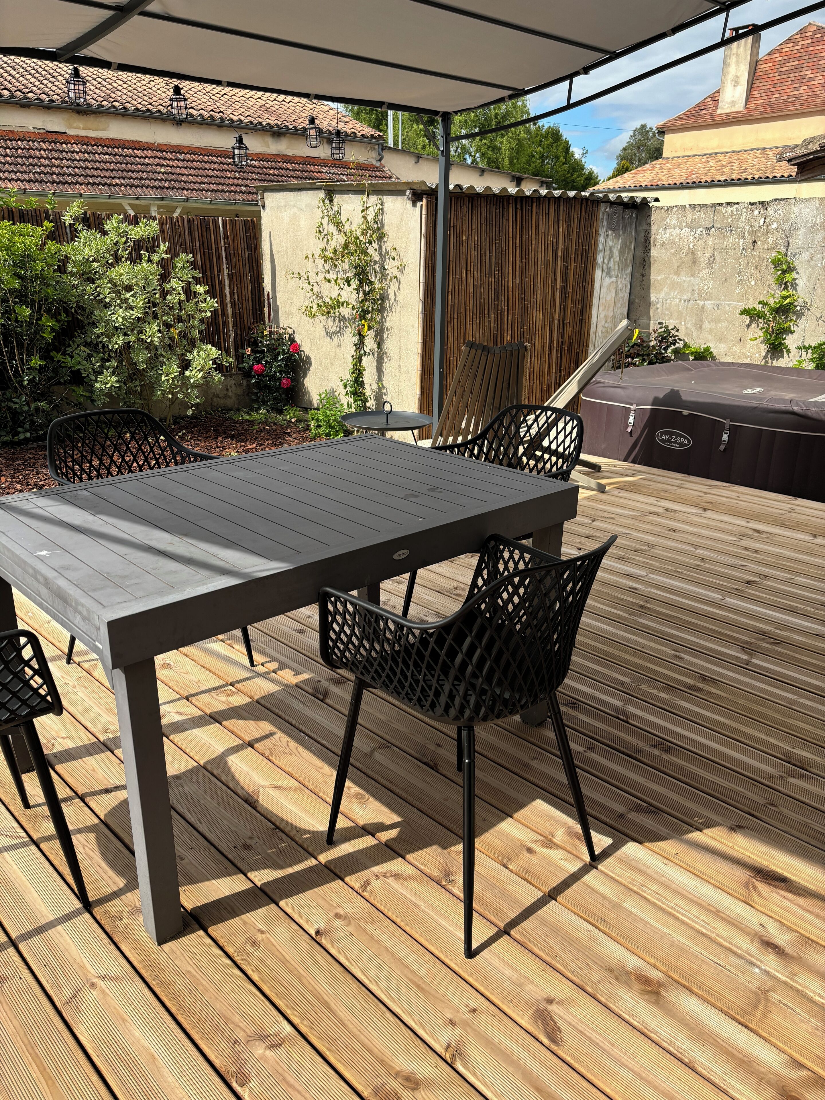 En overdækket terrasse med træterrasse, et bord og stole.