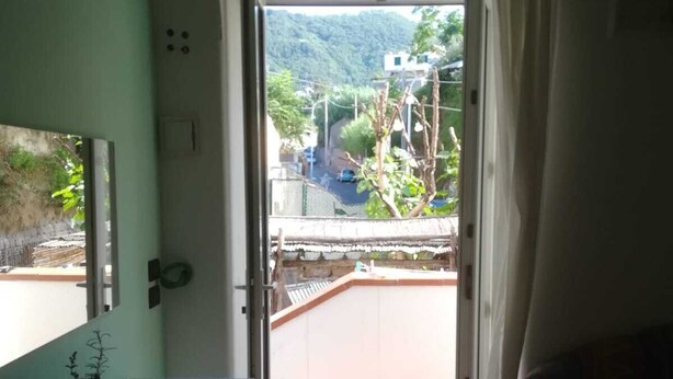 Une pièce dotée d’une porte-fenêtre coulissante donnant sur un balcon avec vue sur une montagne et une route.