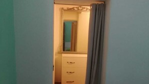 Un couloir étroit mène à une salle de bain équipée d’un miroir et d’un lavabo.