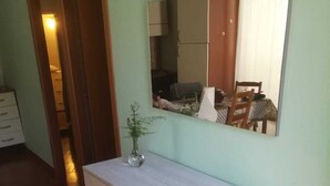 Une salle de bain avec un grand miroir, un meuble-lavabo en bois et une petite plante.