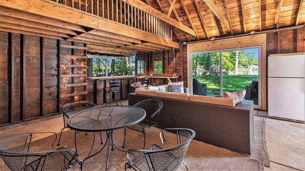 A wooden interior with a dining area, seating, and a view of the outdoors. - Esther House - Beautiful, Newly Renovated Lakehouse on Paw Paw Lake (Watervliet)