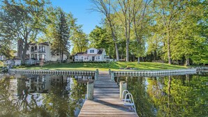 A wooden dock leading to a house with a lawn and trees. - Esther House - Beautiful, Newly Renovated Lakehouse on Paw Paw Lake (Watervliet)