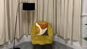 A corner room with a yellow armchair, a black floor lamp, and a large window with beige curtains. - Remarkable 3-bed House in Liverpool (Liverpool)