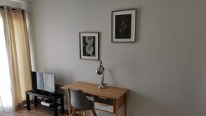 Een kamer met een houten bureau, een zwarte stoel, een ingelijste foto aan de muur en een raam met gordijnen.