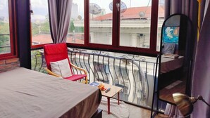 A balcony with a red chair, a small table, and a bed.