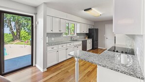 A modern kitchen with white cabinets, granite countertops, and a black refrigerator.