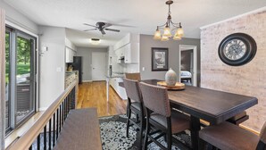 A modern kitchen with white cabinets, a black refrigerator, and a ceiling fan.