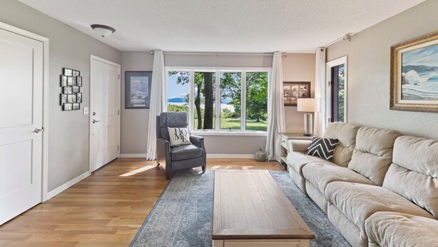 A living room with a sofa, a chair, a coffee table, and a view of the outdoors.