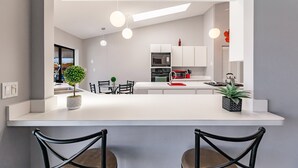 A modern kitchen with white cabinetry, a central island, and pendant lighting. - Paradise Found! Luxurious Private Waterfront Vacation Home with Pool.  (Punta Gorda)