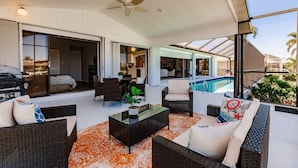 A spacious outdoor living area with wicker furniture, a glass coffee table, and a view of a swimming pool. - Paradise Found! Luxurious Private Waterfront Vacation Home with Pool.  (Punta Gorda)