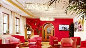 Quarto com paredes vermelhas, um candelabro e mobiliário em vermelho.
